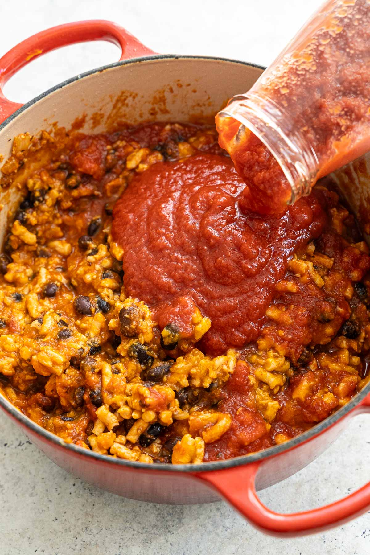 Adding tomato sauce to the pot