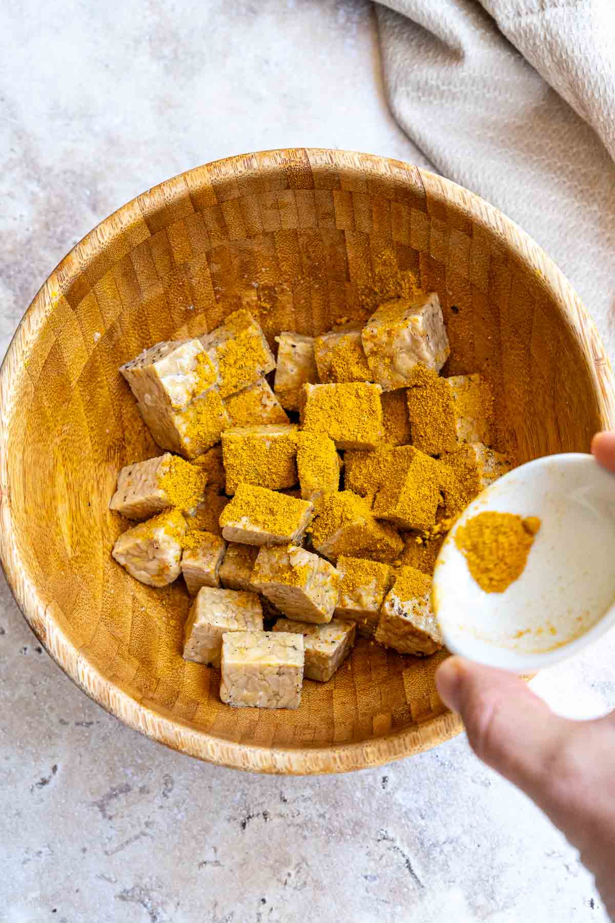 Mixing cut tempeh with spices and oil.