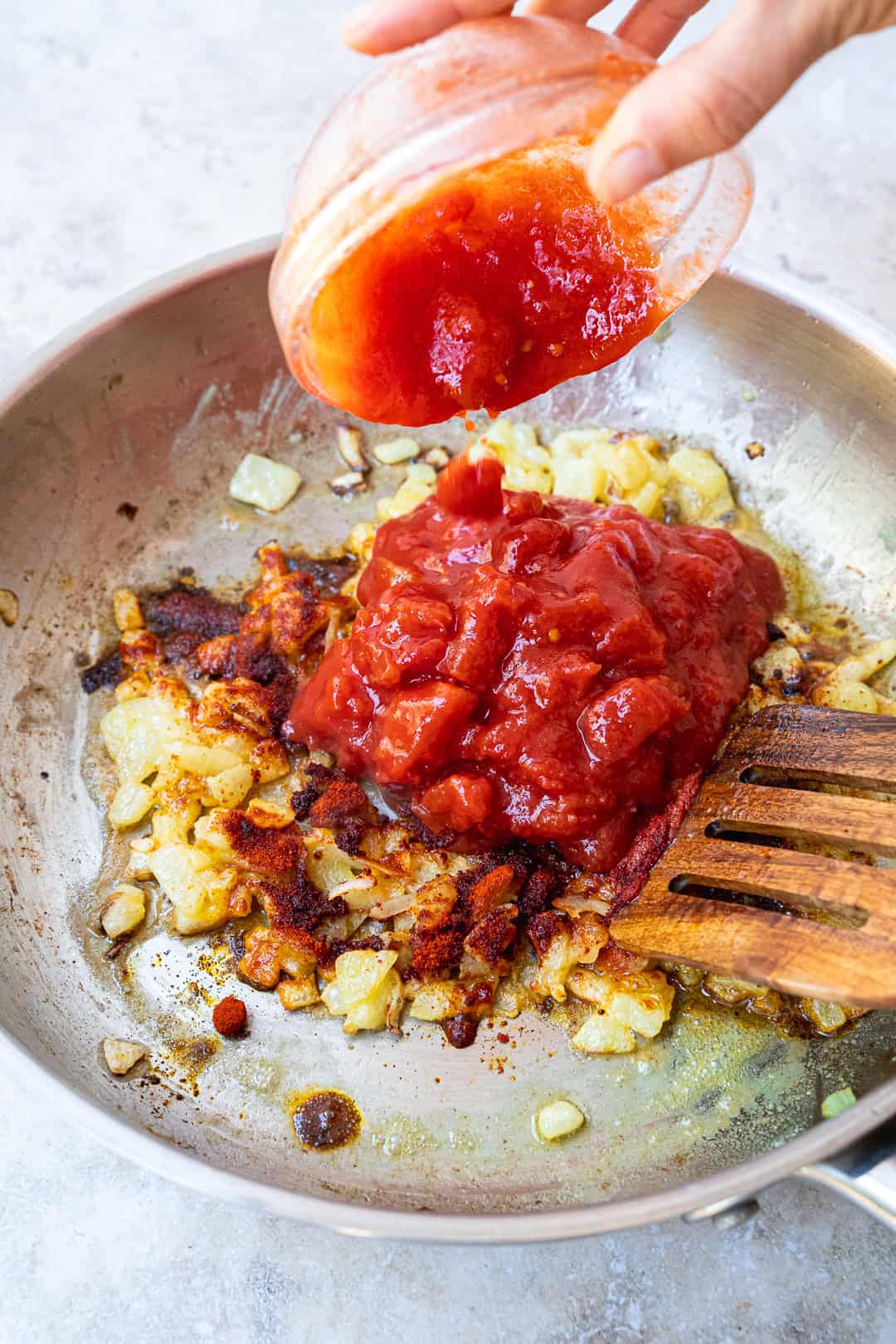 Adding chopped tomatoes, sweet paprika, and tomato paste to the pan. 
