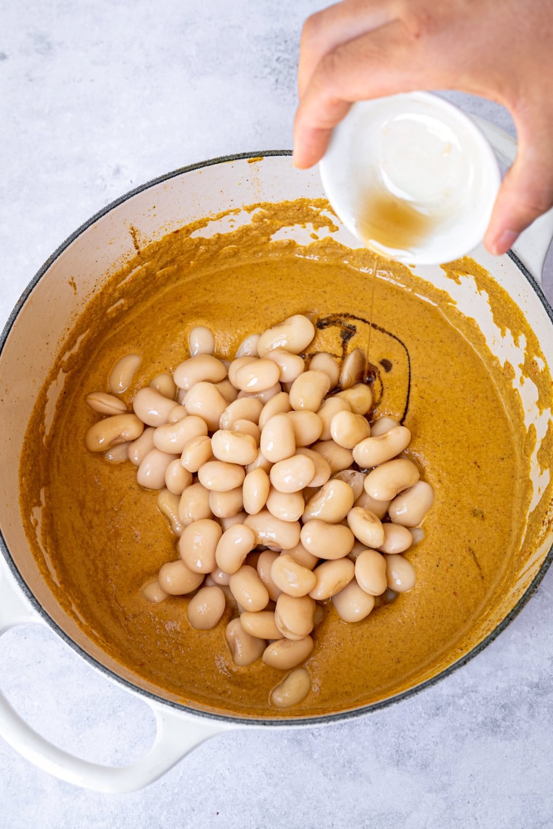 Transferring blended sauce to the pot with the butter beans, and sweetener.