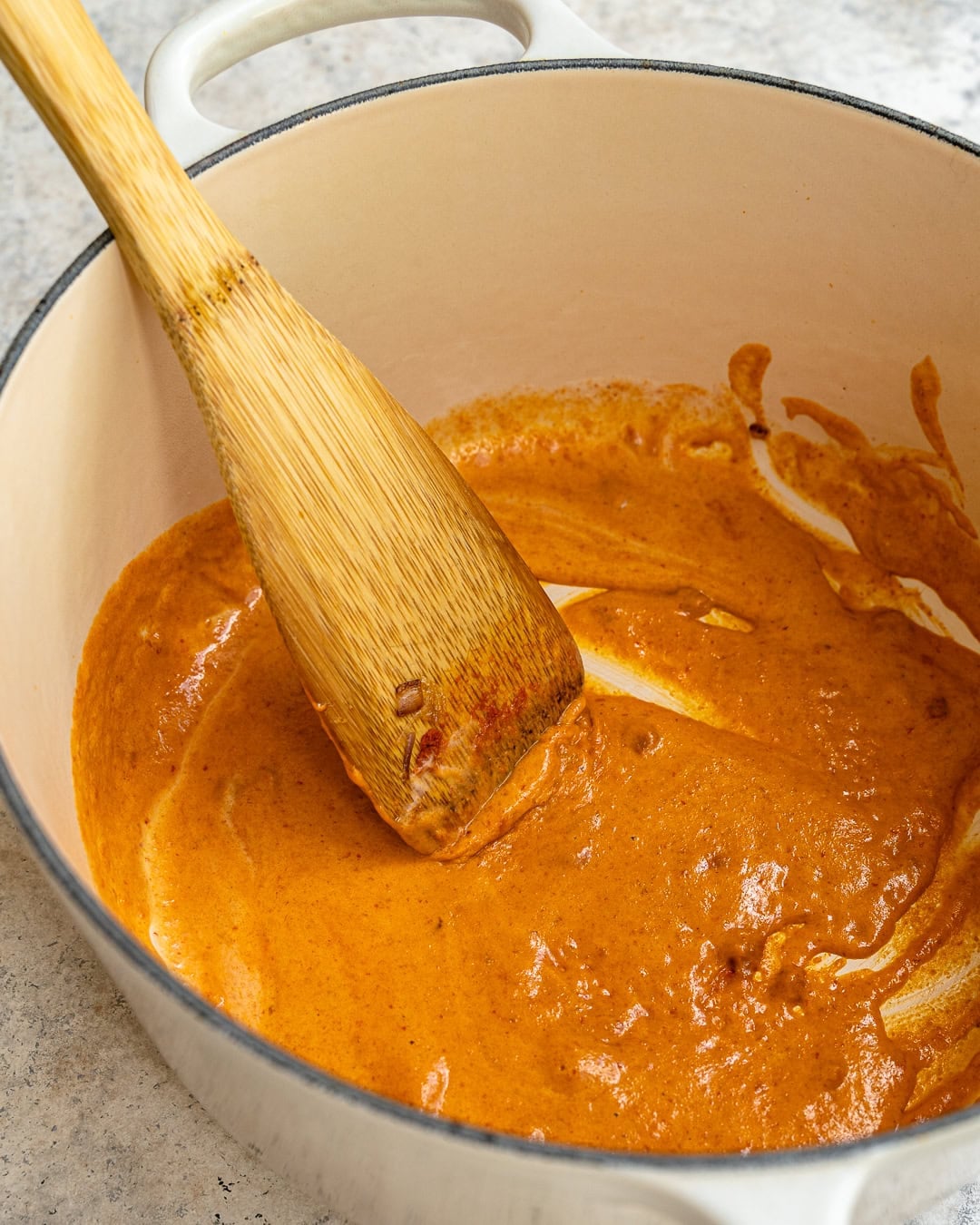 stirring the butternut squash sauce with some curry paste.