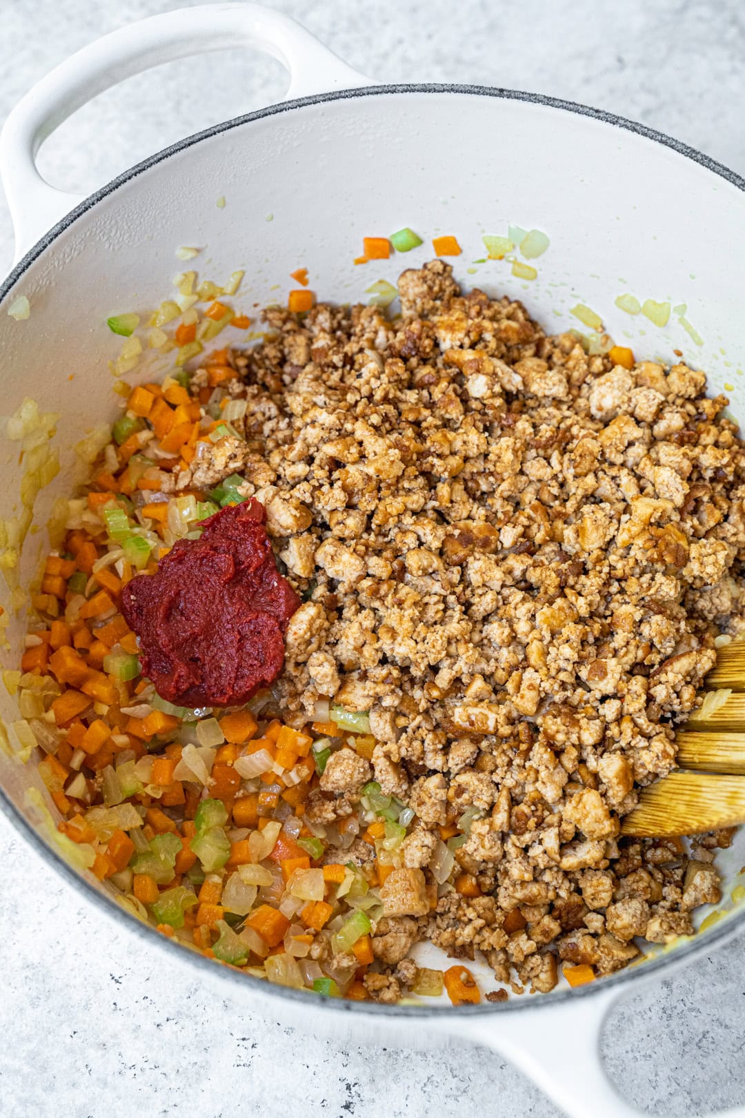 Combining the veggies and tofu with tomato paste.
