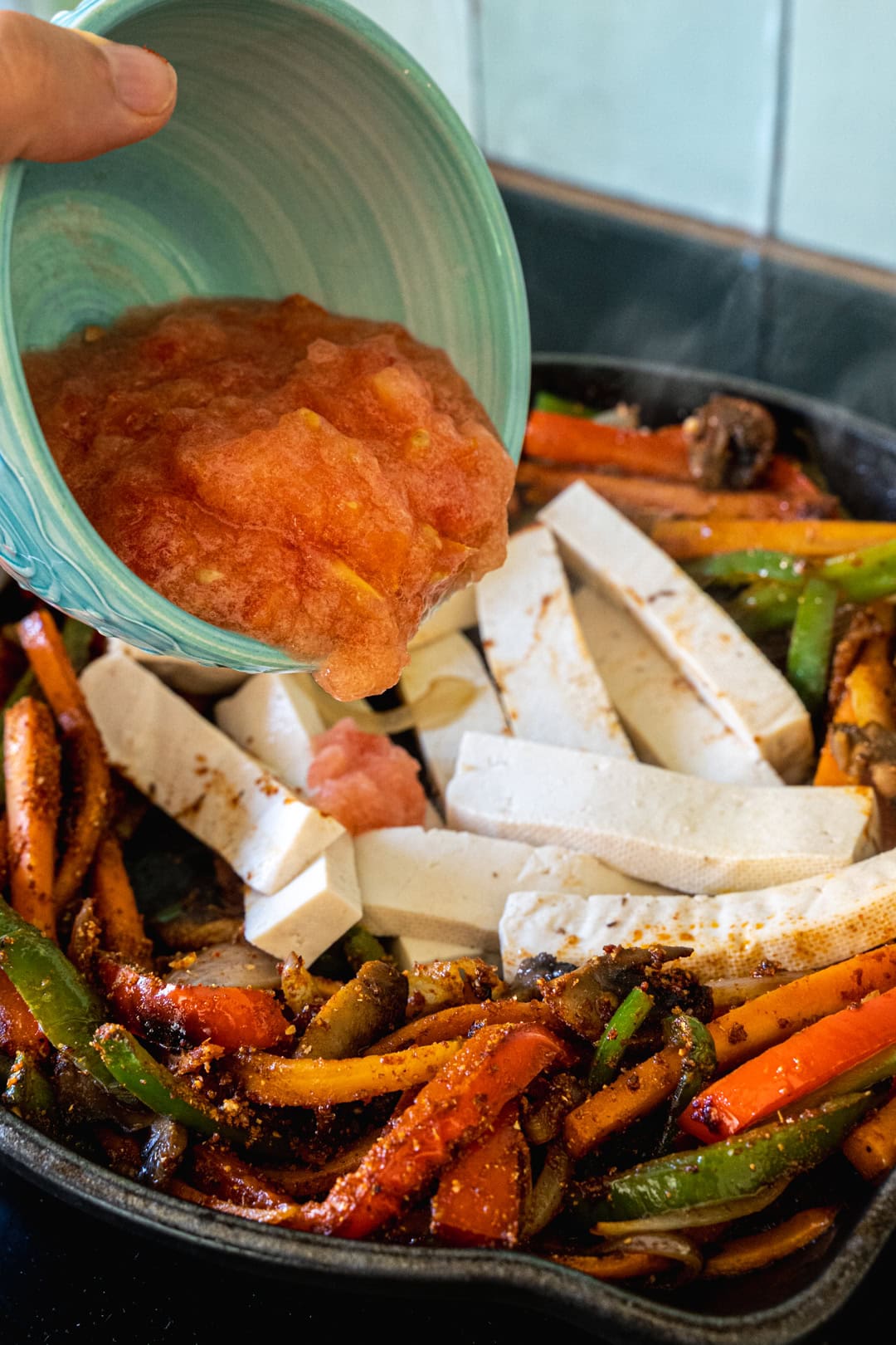 Adding tofu and tomato puree to the skillet pan 
