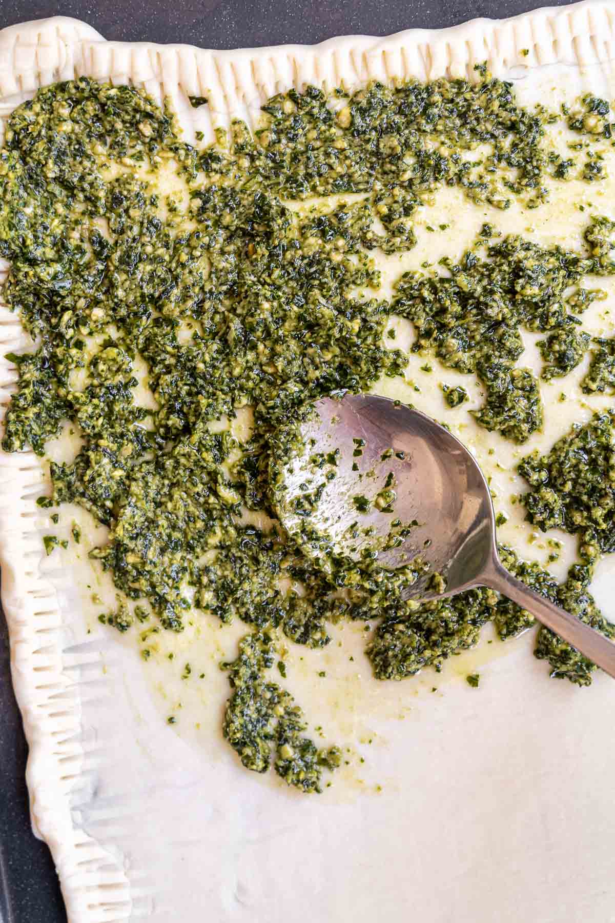 adding pesto to the puff pastry