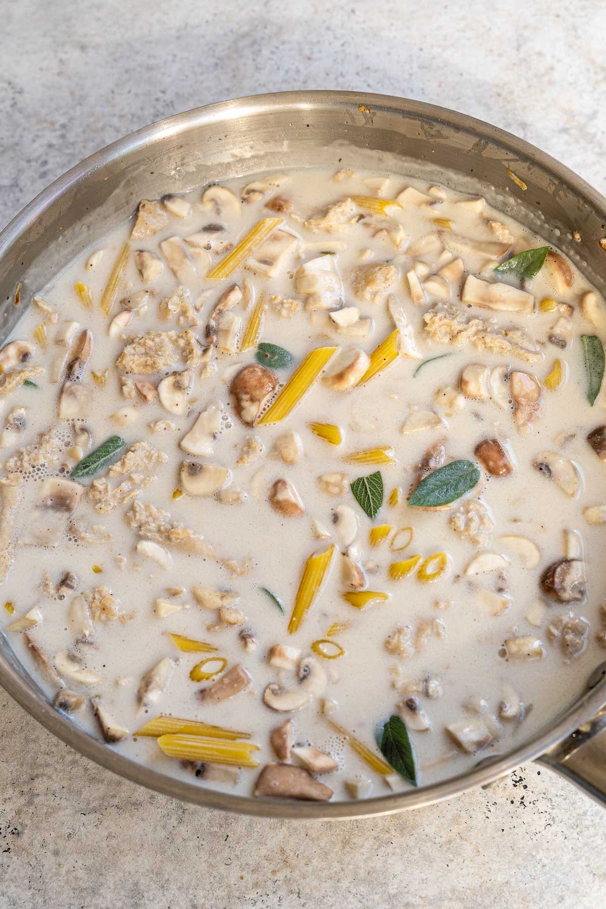 Adding the pasta, stock, oat cream and sage.